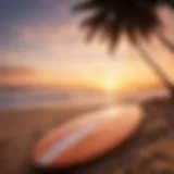 Surfboard resting on the beach with vibrant sunset in the background